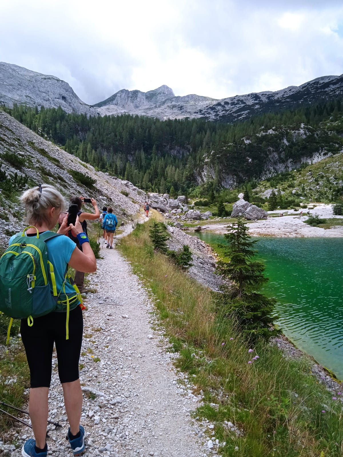 Escursionisti che camminano lungo un sentiero alpino accanto al fiume Isonzo, Slovenia.
